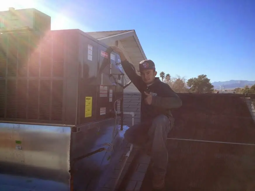 HVAC technician performing Air Duct Repair on a rooftop unit in Harrison